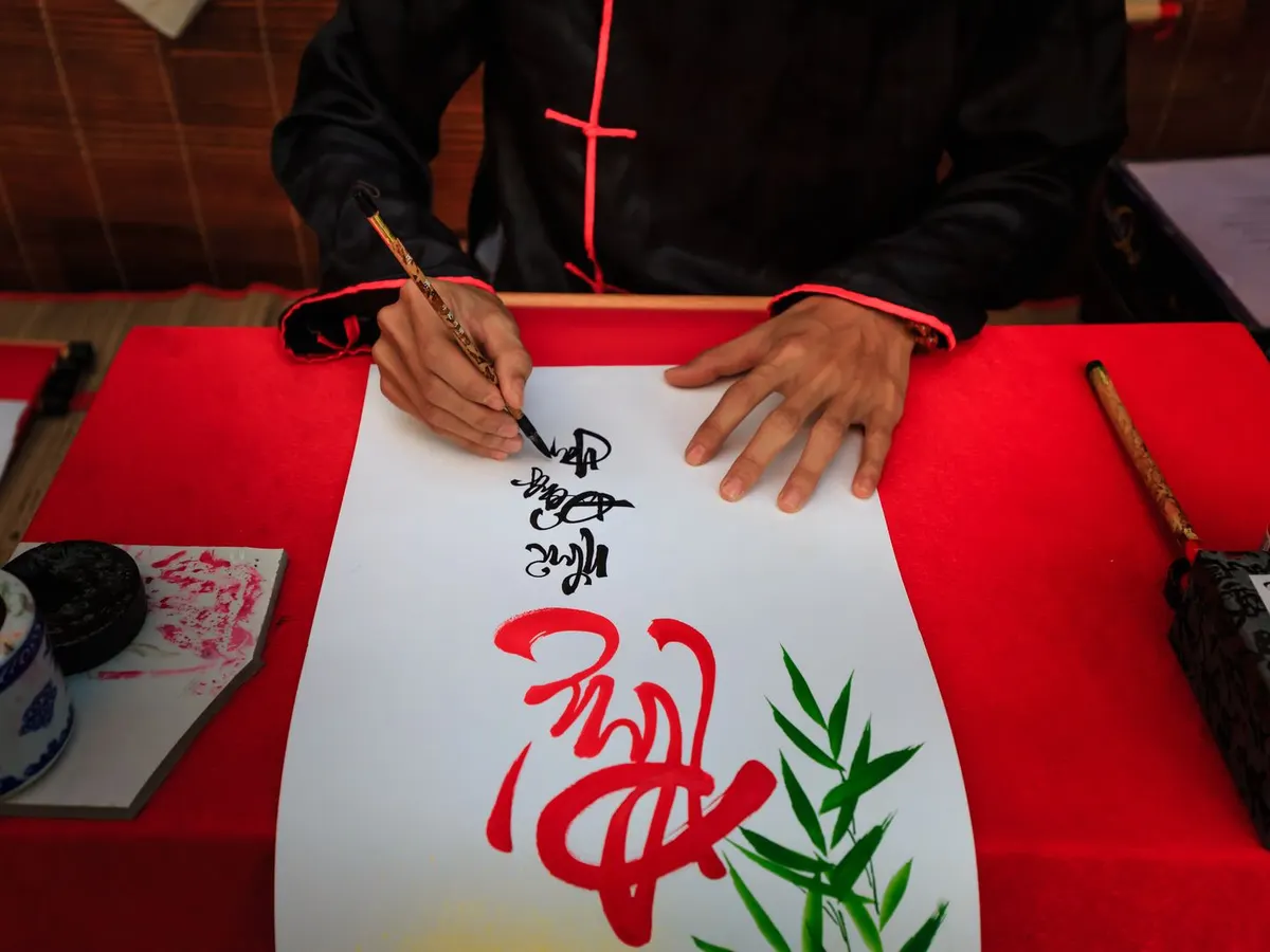 Ilustrasi menulis kaligrafi Mandarin dengan kuas di atas kertas merah
